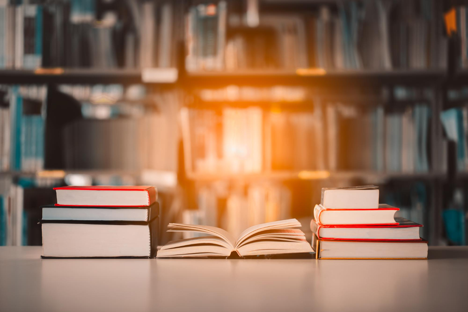An open academic book between two stacks of books